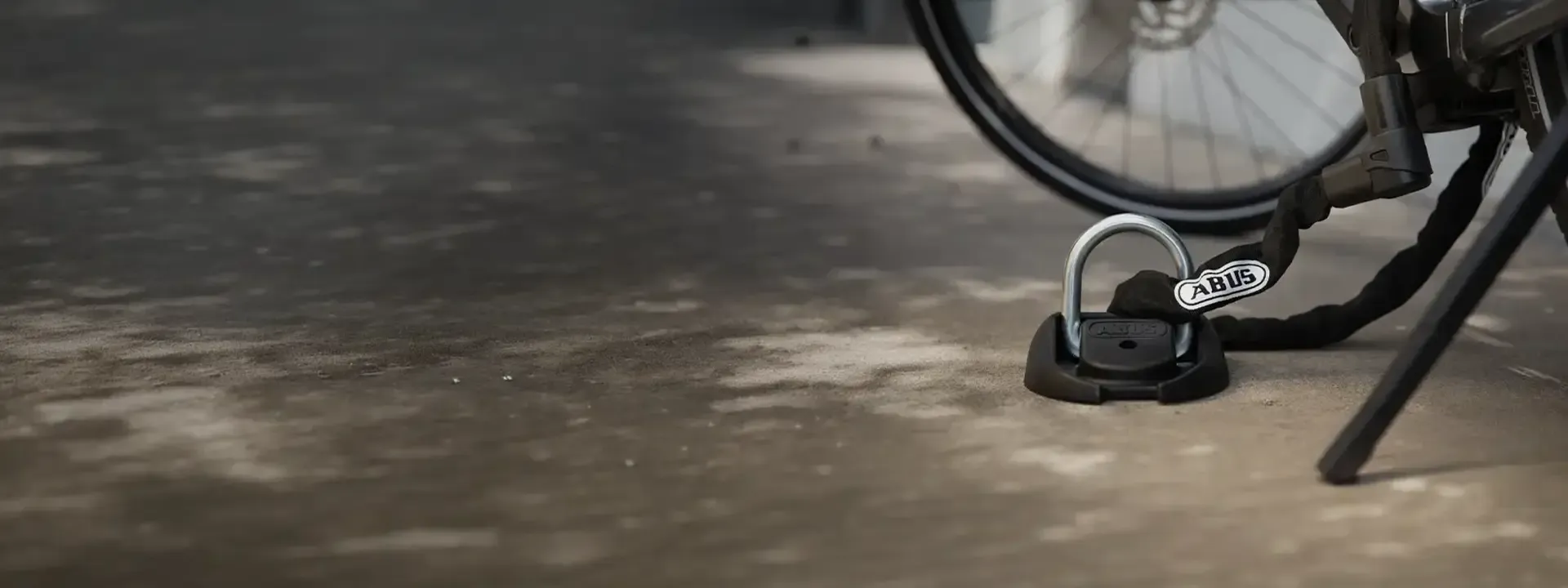 Bicycle chain secured through a fixed ground anchor