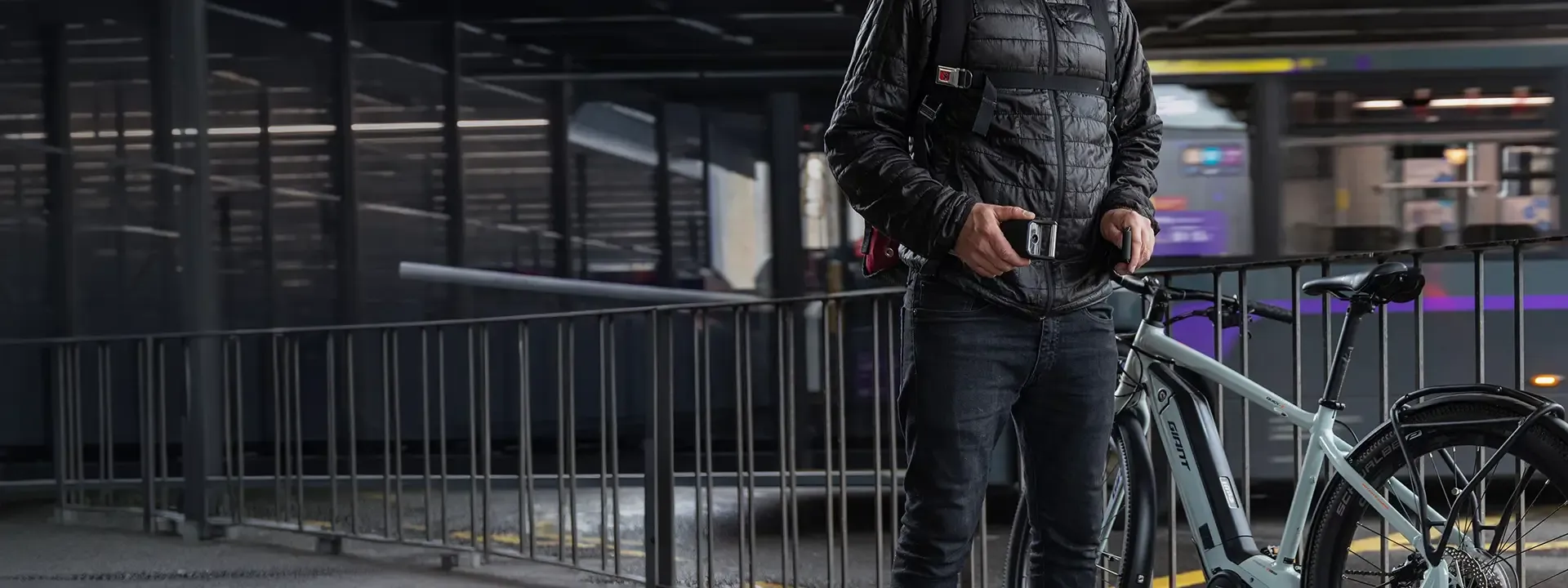 Cyclist carrying a Hiplok wearable bike lock beside an urban bicycle