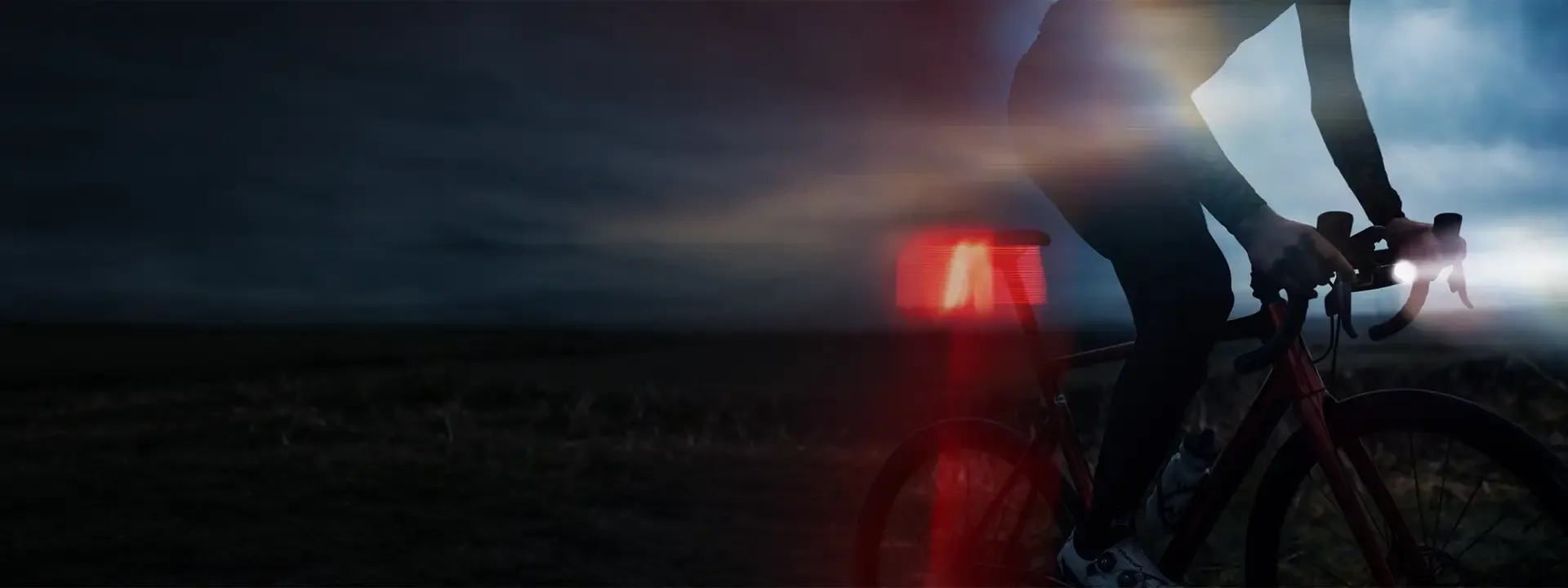 Road cyclist riding at dusk with front and rear bike lights illuminated