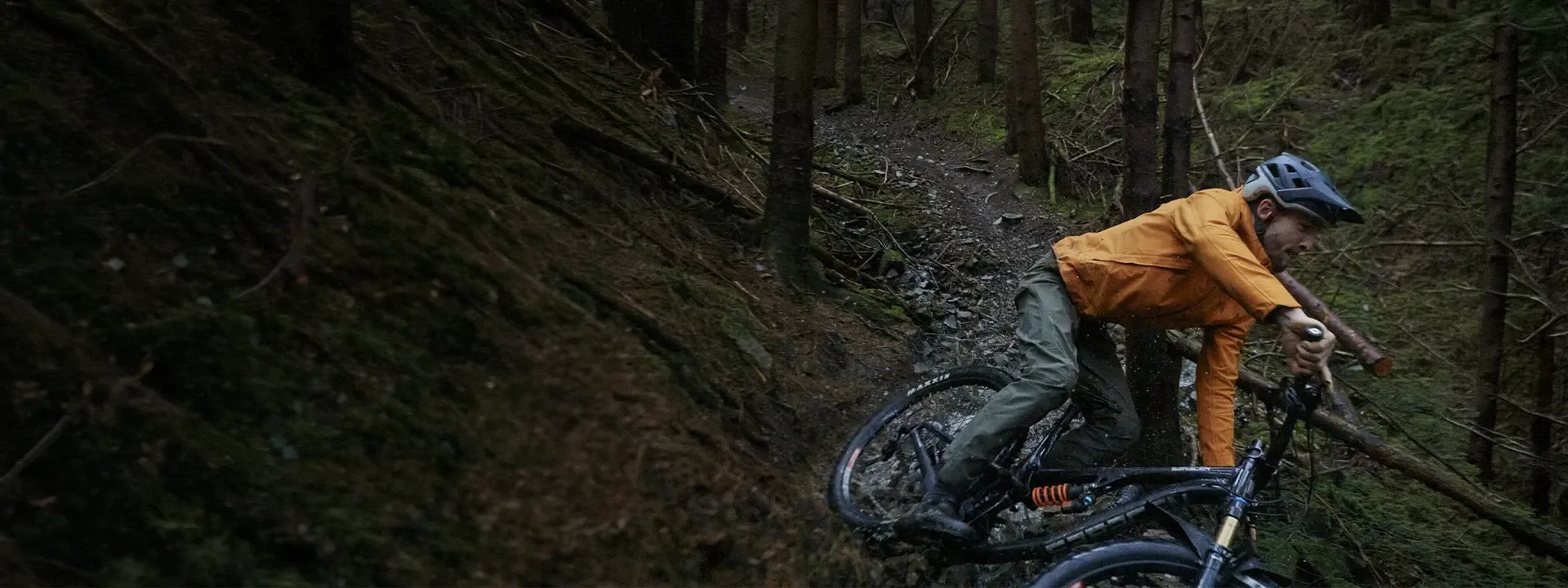 Mountain biker riding in heavy rain wearing a waterproof MTB jacket