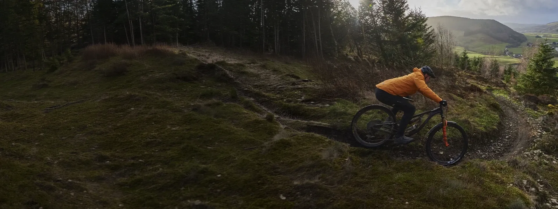 Mountain biker wearing a protective MTB jacket on a woodland trail