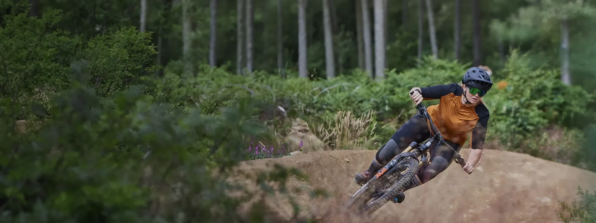 Mountain biker wearing a technical MTB jersey on a forest trail