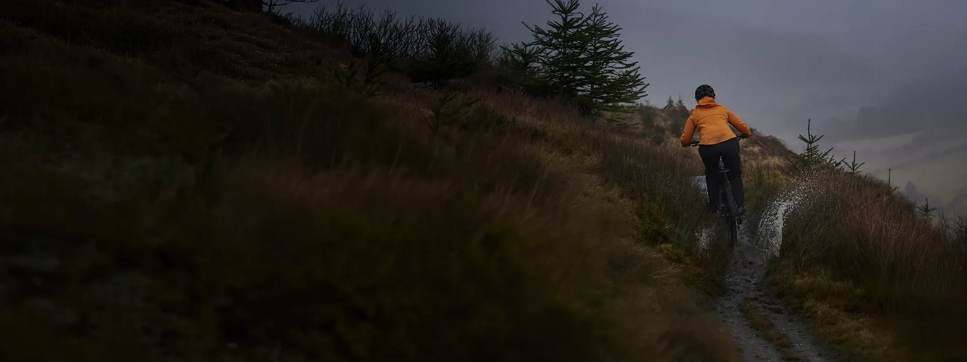 Mountain biker riding in heavy rain wearing waterproof MTB trousers