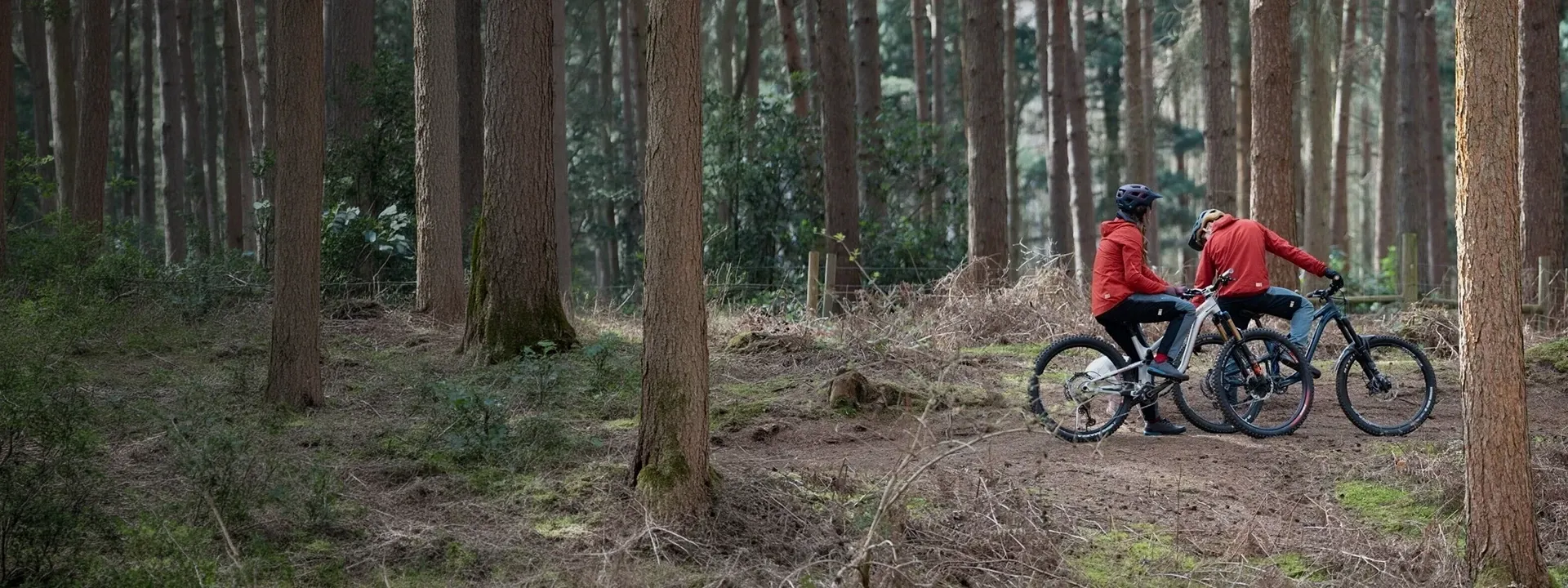 Mountain biker riding through forest trail wearing technical MTB clothing