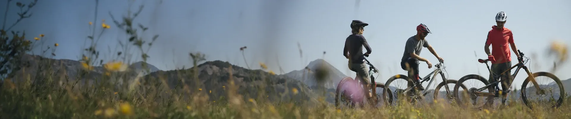 Mountain bikers at a trail head wearing technical MTB clothing in alpine terrain