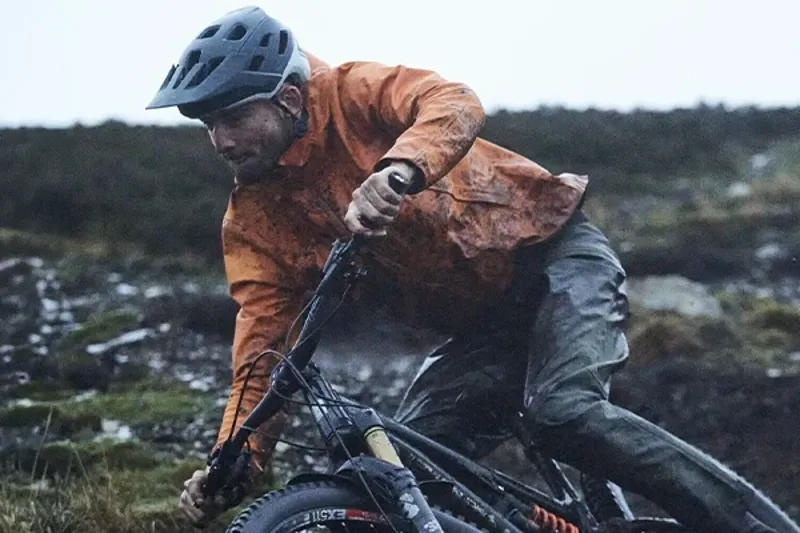 Mountain biker wearing a lightweight jacket on a wet and muddy trail ride