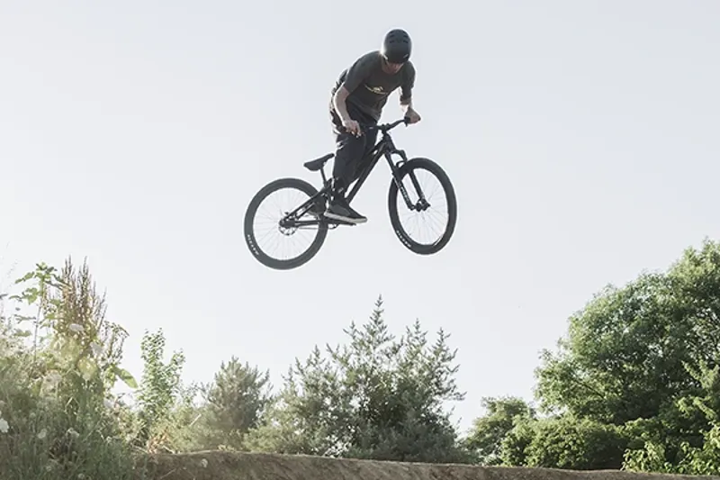 Dirt jump bike mid-air over a jump