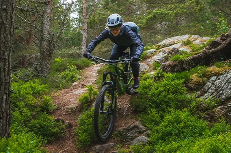 Female mountain biker descending a rocky trail showing suspension working
