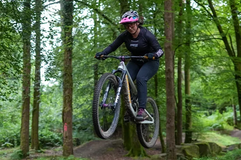 Woman riding a Santa Cruz mountain bike on jumps in the woods