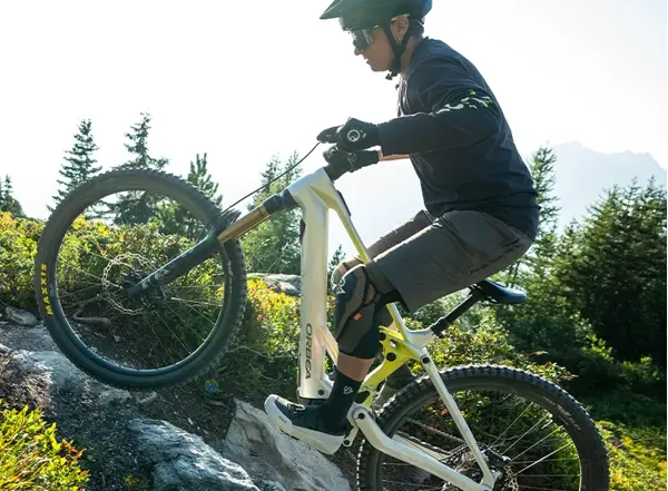 Rider climbing on eMTB wearing MTB shorts and knee pads