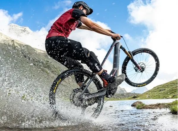 Rider wearing durable MTB riding trousers crossing a stream