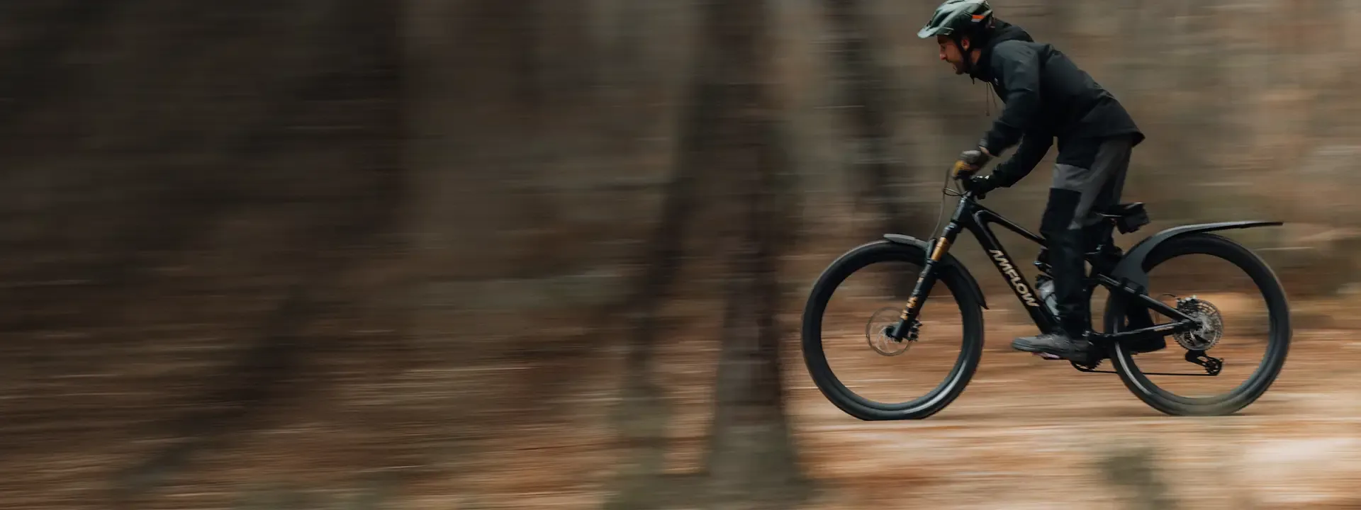 Mountain biker riding through woodland with mudguards fitted