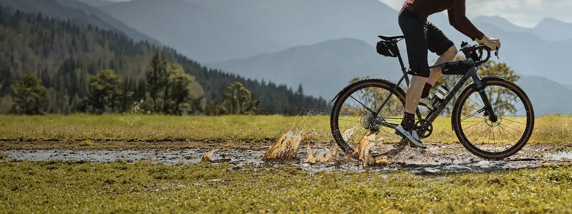 Cyclist riding through wet ground with mudguards fitted to the bike