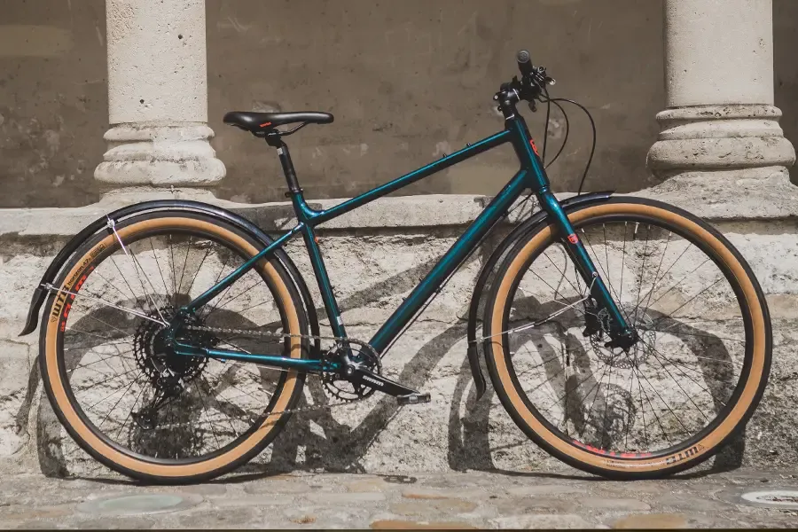 Hybrid bike with full-length mudguards parked beside stone columns