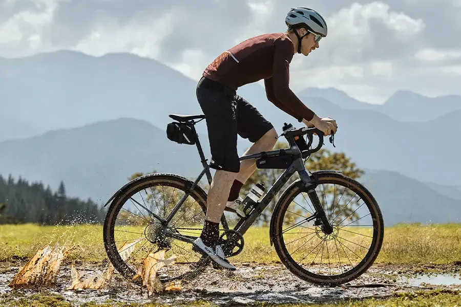Gravel cyclist riding a rough track with mountains in the background