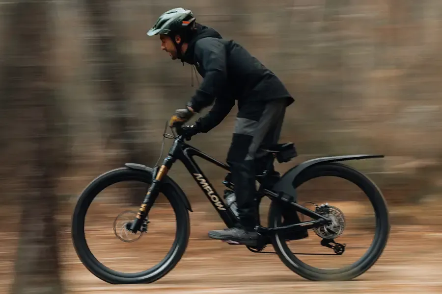 Mountain biker riding through woodland with front and rear mudguards fitted