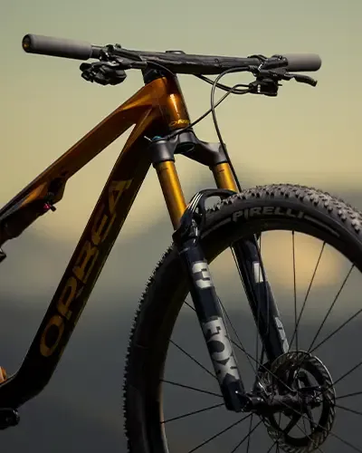 Front end of an orange Orbea Oiz showing the handlebar, fork and front wheel