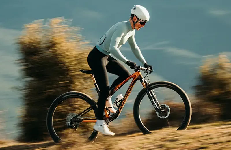 Rider pedalling an orange Orbea Oiz uphill