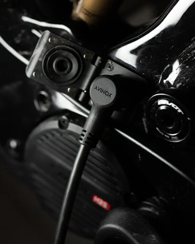 Close-up of Avinox charging port and cable connected to the Pivot Shuttle AMP&rsquo;d frame near the motor.