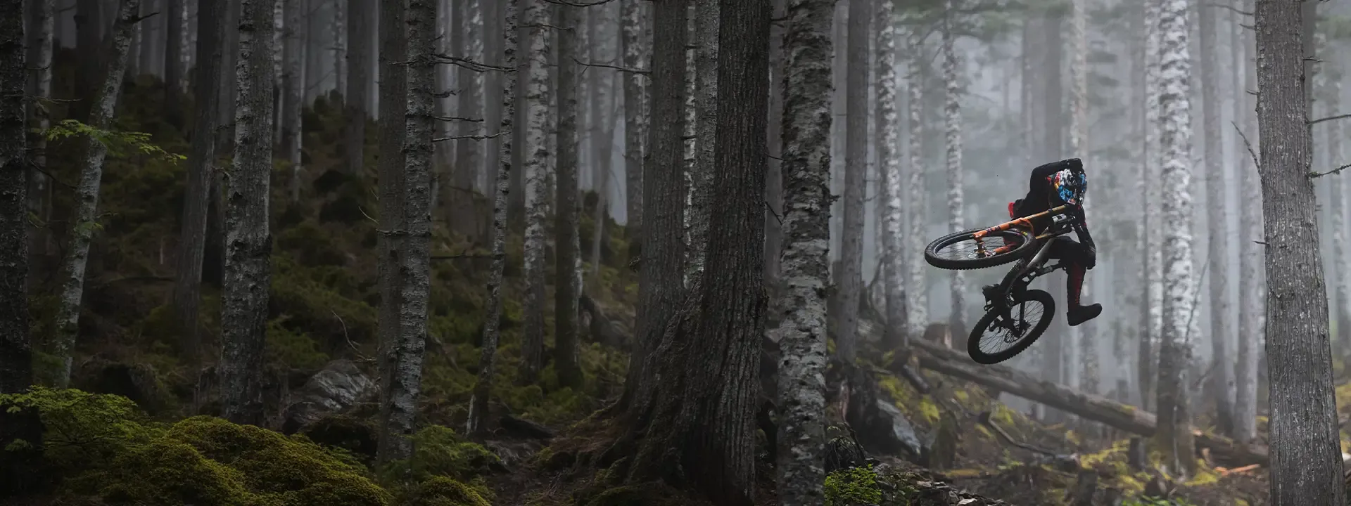 Mountain biker riding through woodland wearing protective riding kit