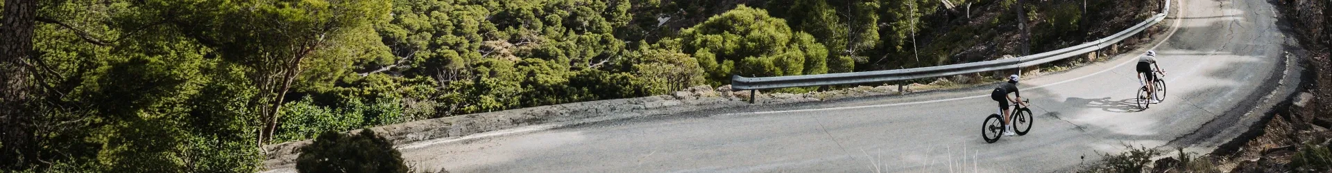 Road cyclists riding through a cutting on a mountain road