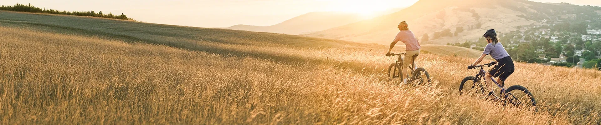 RIding the Trek Marlin+ hardtail electric mountain bike through long grass on a summer day