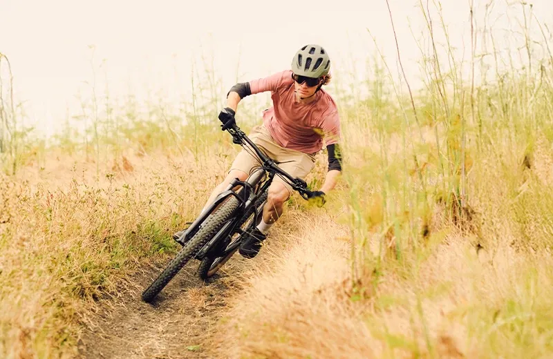 Riding the Trek Marlin+ hardtail eMTB through a singletrack turn on a sunny day